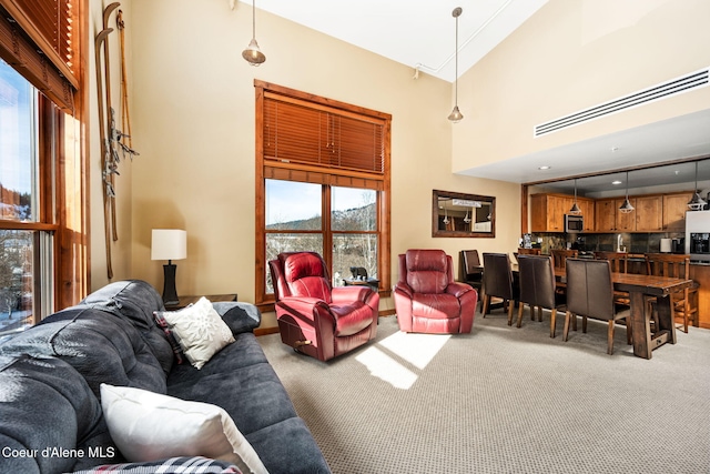 living room featuring a towering ceiling and carpet floors