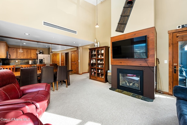 living room featuring a multi sided fireplace, light colored carpet, and a high ceiling