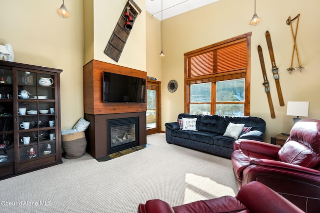 carpeted living room featuring a towering ceiling and a fireplace