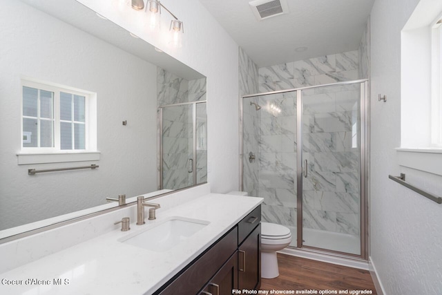 bathroom featuring hardwood / wood-style floors, vanity, a shower with shower door, and toilet