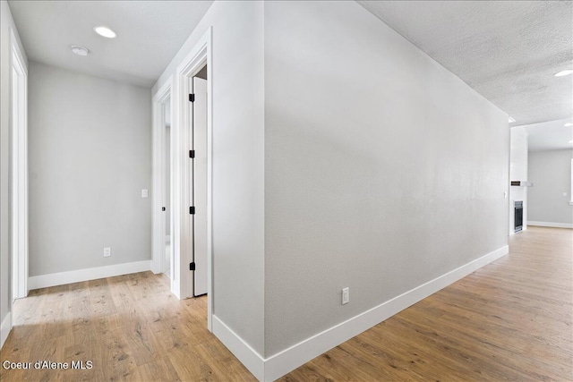 hall with a textured ceiling and light hardwood / wood-style floors