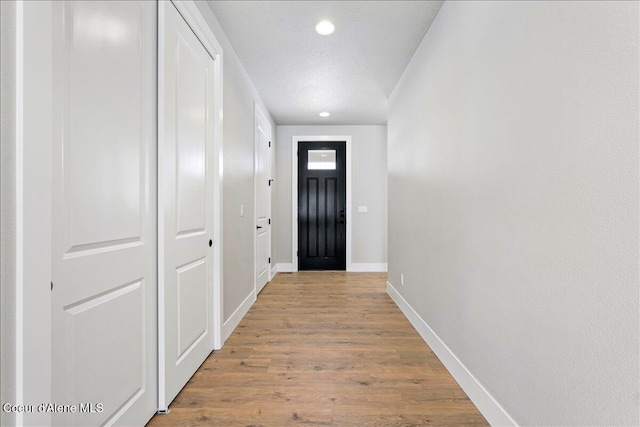 doorway to outside featuring light hardwood / wood-style flooring and a textured ceiling