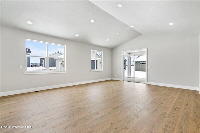 unfurnished room with a textured ceiling, light hardwood / wood-style flooring, and vaulted ceiling