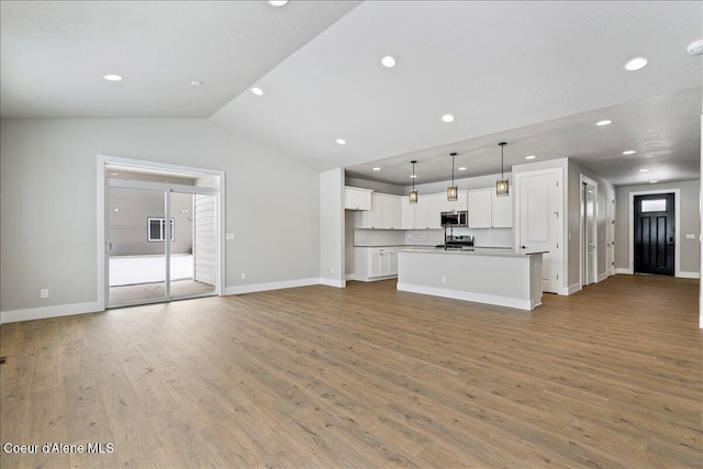 unfurnished living room with vaulted ceiling and light wood-type flooring