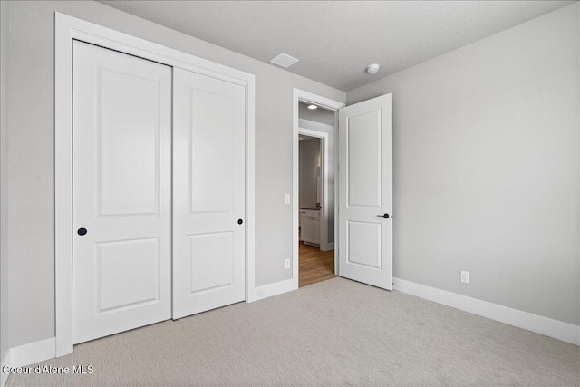 unfurnished bedroom featuring light carpet and a closet