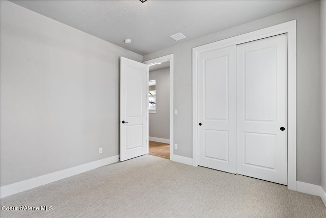 unfurnished bedroom with a closet and light colored carpet