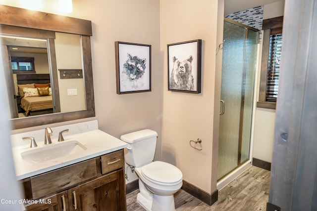 bathroom with hardwood / wood-style flooring, vanity, toilet, and a shower with shower door