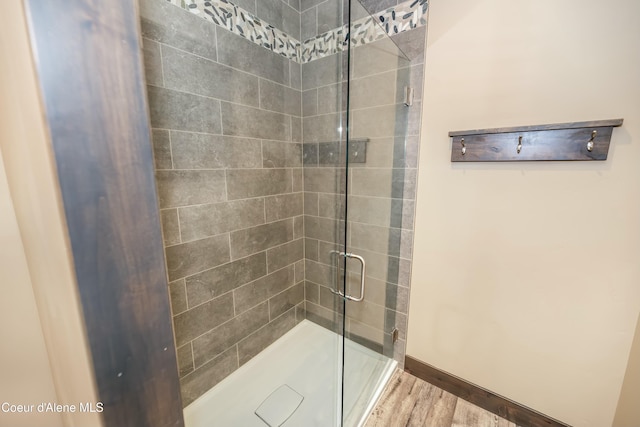 bathroom with a shower with shower door and hardwood / wood-style flooring