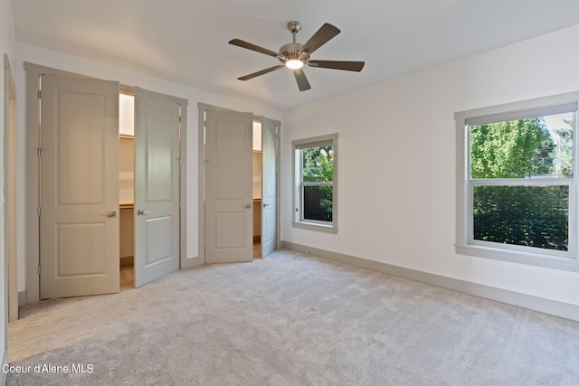 unfurnished bedroom with ceiling fan, light colored carpet, and multiple windows