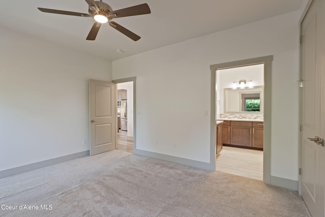 unfurnished bedroom with light carpet, sink, ensuite bathroom, and ceiling fan