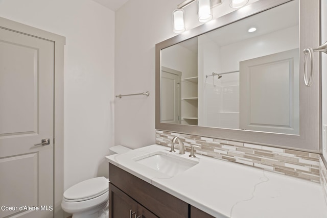 bathroom featuring vanity, toilet, a shower, and tasteful backsplash