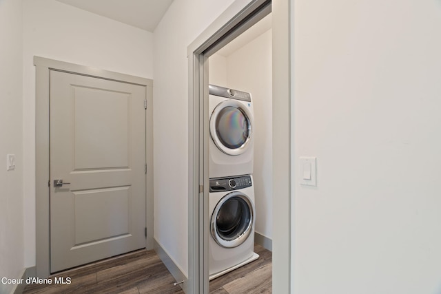 laundry area with dark hardwood / wood-style flooring and stacked washer and dryer