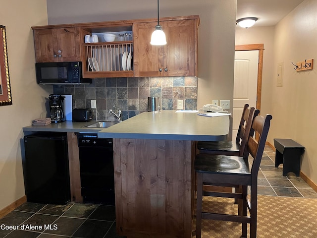 kitchen featuring black appliances, a kitchen breakfast bar, sink, hanging light fixtures, and tasteful backsplash