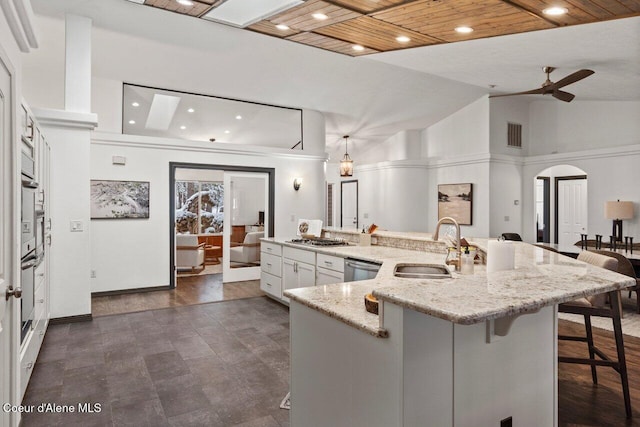 kitchen with white cabinetry, sink, a kitchen breakfast bar, a spacious island, and wood ceiling