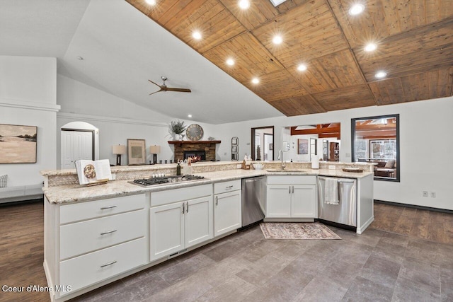 kitchen with wooden ceiling, white cabinets, a stone fireplace, sink, and appliances with stainless steel finishes