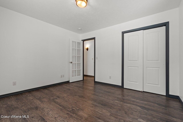 unfurnished bedroom featuring french doors, dark hardwood / wood-style flooring, a textured ceiling, and a closet