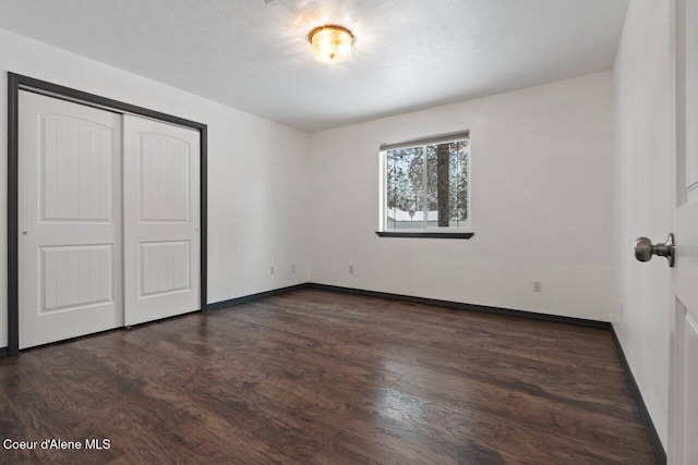 unfurnished bedroom featuring dark hardwood / wood-style flooring, a textured ceiling, and a closet