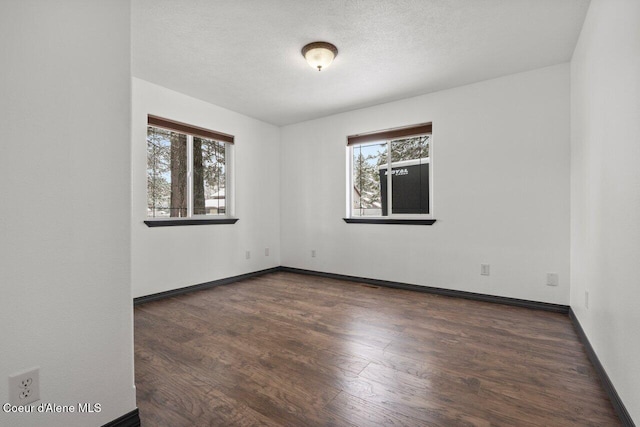 empty room with dark wood-type flooring and a wealth of natural light