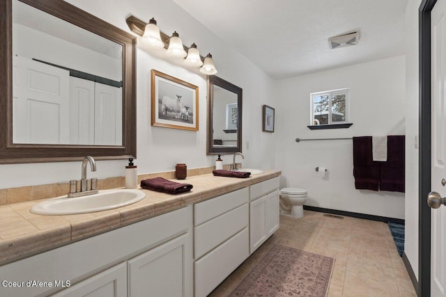 bathroom featuring a textured ceiling, vanity, toilet, and tile patterned floors