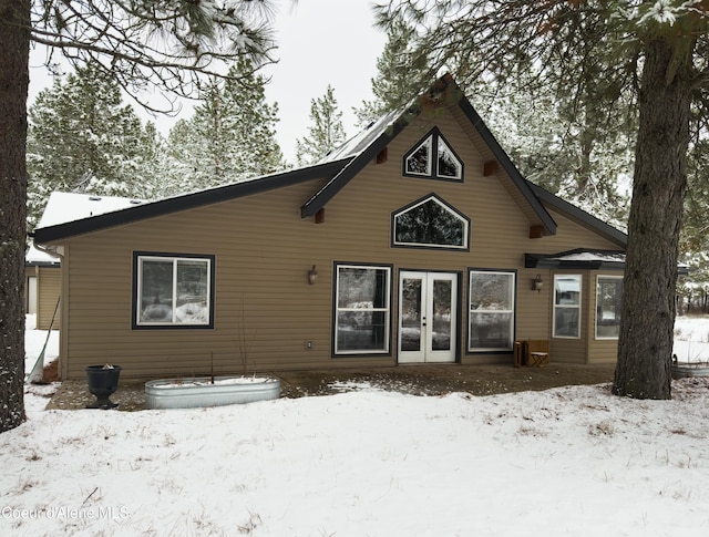 snow covered rear of property with french doors