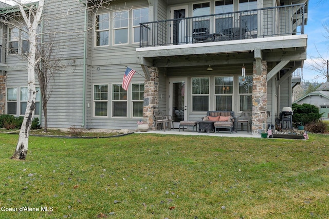 rear view of house with outdoor lounge area, a yard, a balcony, and a patio area