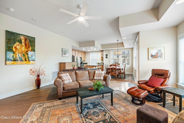 living room featuring wood-type flooring and ceiling fan with notable chandelier