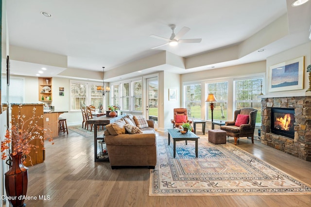 living room with a stone fireplace, ceiling fan, and hardwood / wood-style flooring