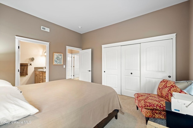 carpeted bedroom featuring ensuite bath, sink, and a closet