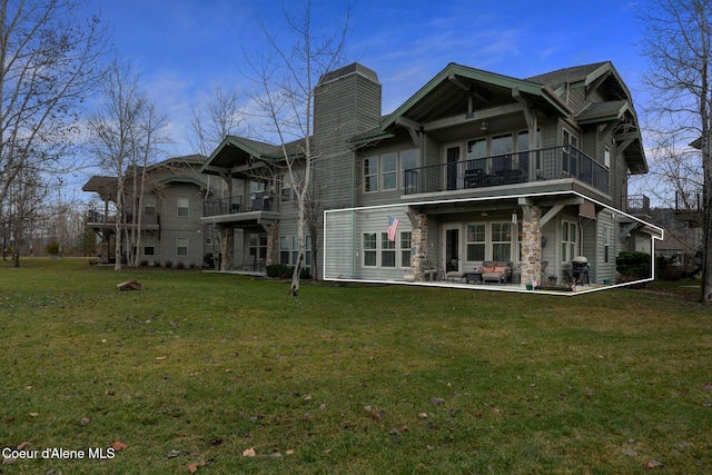 back of property with a patio, a balcony, and a lawn