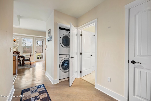 clothes washing area with light hardwood / wood-style flooring and stacked washer and clothes dryer