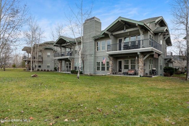 rear view of house featuring a balcony and a yard