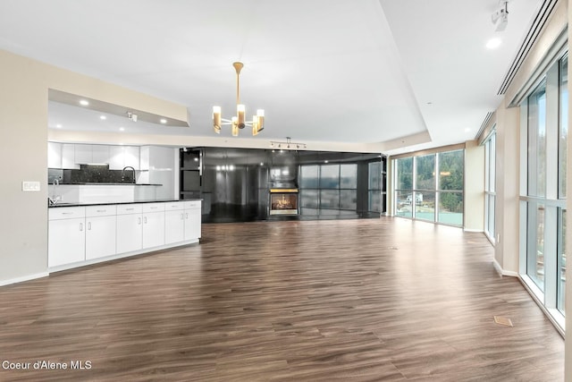 unfurnished living room with a chandelier, dark hardwood / wood-style floors, floor to ceiling windows, and sink