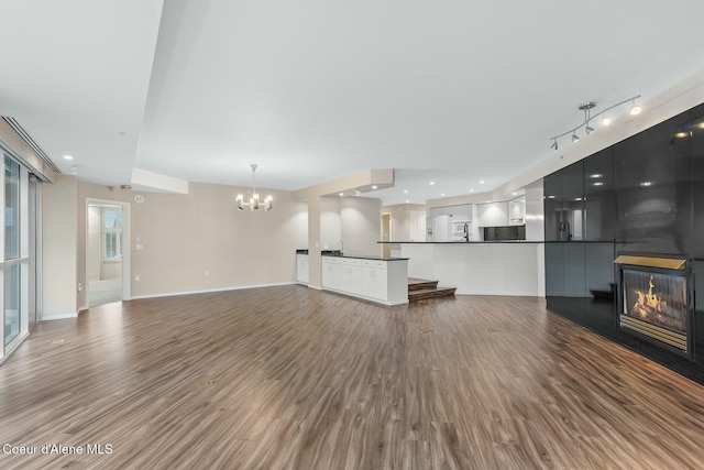 unfurnished living room with a chandelier, a fireplace, hardwood / wood-style floors, and track lighting