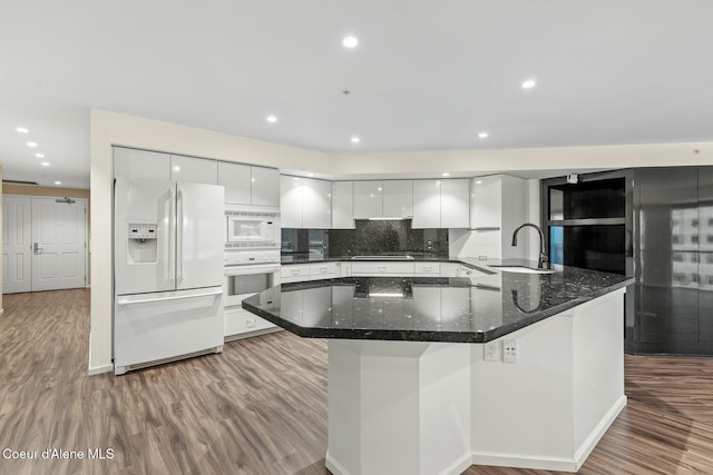 kitchen featuring tasteful backsplash, white appliances, sink, dark stone countertops, and white cabinets