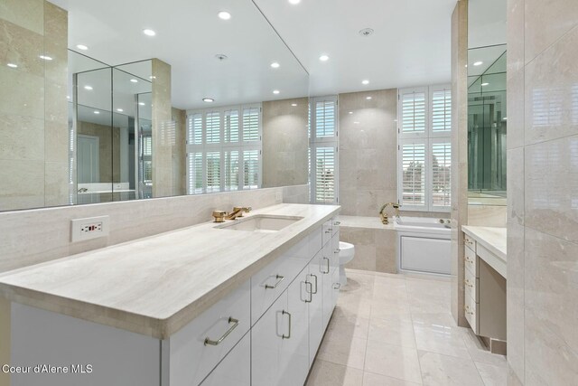 bathroom featuring a wealth of natural light, vanity, toilet, and tile walls