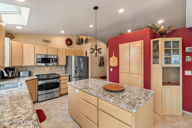 kitchen with a center island, hanging light fixtures, stainless steel appliances, tasteful backsplash, and lofted ceiling with skylight