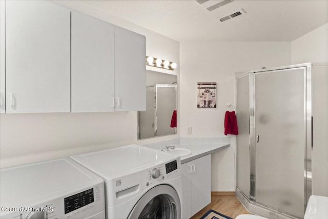 laundry area featuring cabinets, sink, washer and dryer, and light hardwood / wood-style floors