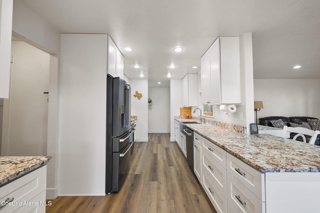 kitchen with white cabinets, high end refrigerator, light stone countertops, and hardwood / wood-style floors