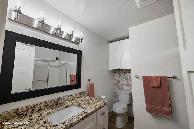 bathroom featuring hardwood / wood-style floors, vanity, toilet, a textured ceiling, and walk in shower