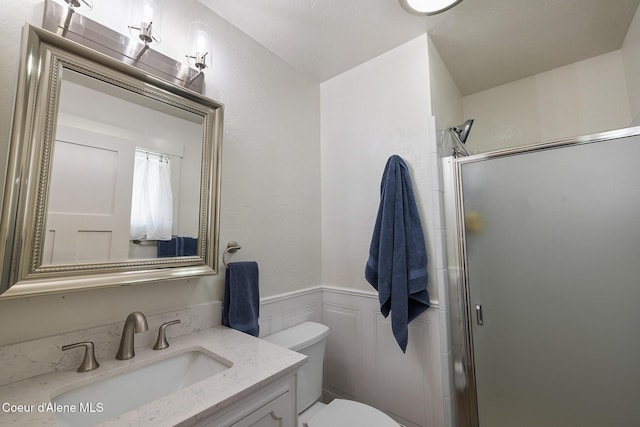 bathroom featuring vanity, toilet, and a shower with shower door