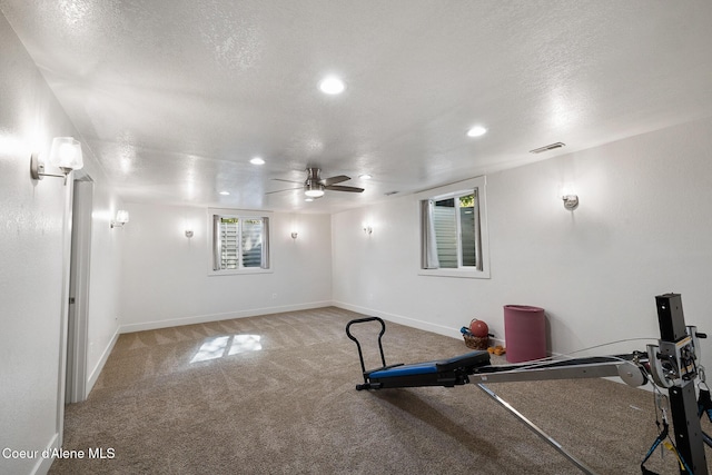 exercise room featuring carpet flooring, ceiling fan, and a textured ceiling