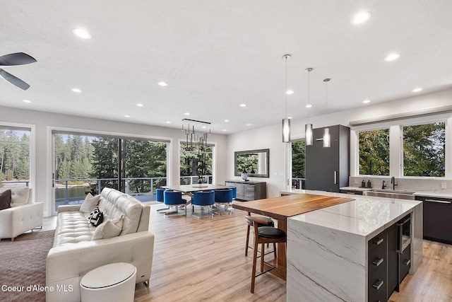 kitchen with open floor plan, hanging light fixtures, a large island, and a sink