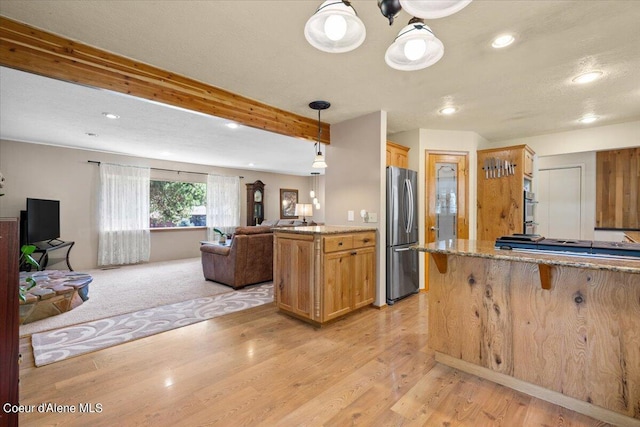 kitchen featuring appliances with stainless steel finishes, light wood-type flooring, pendant lighting, beamed ceiling, and a breakfast bar area