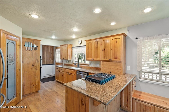 kitchen with light stone counters, sink, stainless steel dishwasher, and a textured ceiling