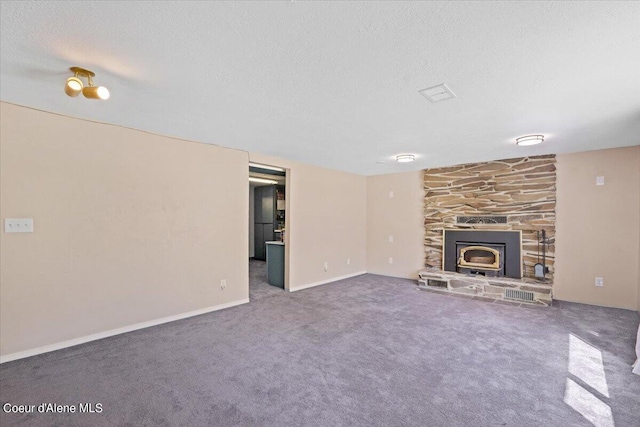 unfurnished living room with carpet flooring, a textured ceiling, and a wood stove