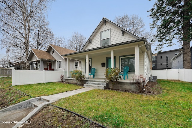 bungalow with cooling unit, covered porch, and a front yard