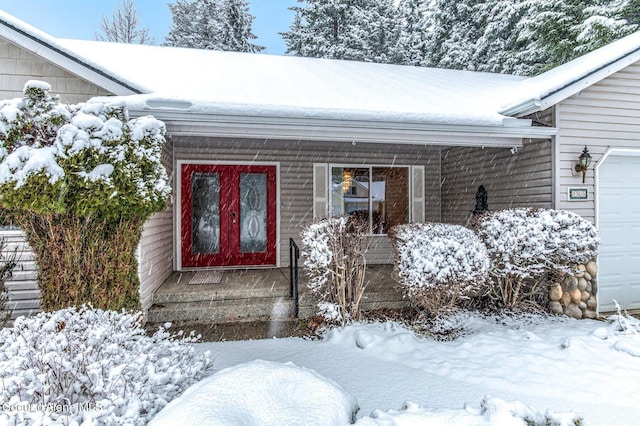 snow covered property entrance with a garage