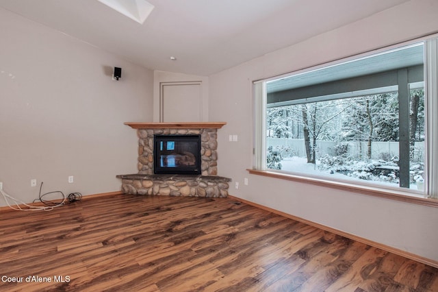 unfurnished living room featuring a fireplace, wood-type flooring, and vaulted ceiling with skylight