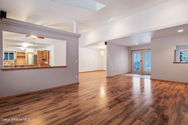 unfurnished living room featuring french doors, a skylight, ceiling fan, and wood-type flooring