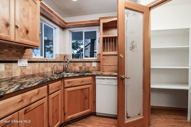 kitchen featuring white dishwasher, dark stone countertops, sink, and light hardwood / wood-style flooring